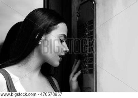 Lady In Red With Intercom, Interphone. Young Woman Posing On A City Background. Beautiful Young Brun