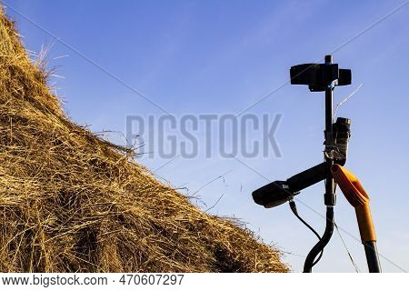 Metal Detector And Sapper Shovel On A Haystack In An Open Field Against The Blue Sky
