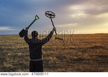 A Happy Treasure Hunter With A Metal Detector On The Background Of A Beautiful Sunset