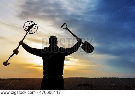 A Happy Treasure Hunter With A Metal Detector On The Background Of A Beautiful Sunset