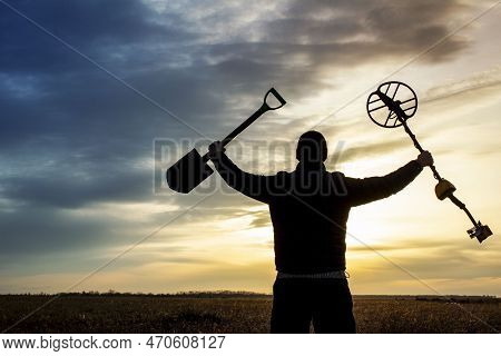 A Happy Treasure Hunter With A Metal Detector On The Background Of A Beautiful Sunset