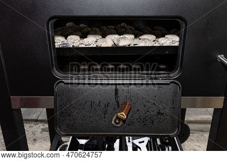 Cleaning A Dirty Grill While Standing On The Terrace And Emptying The Ashes.