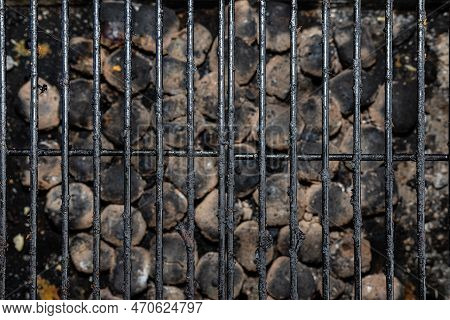 Cleaning A Dirty Grill While Standing On The Terrace And Emptying The Ashes.