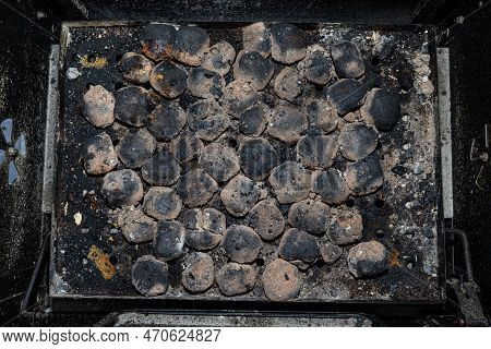 Cleaning A Dirty Grill While Standing On The Terrace And Emptying The Ashes.