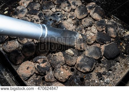 Cleaning A Dirty Grill While Standing On The Terrace And Emptying The Ashes.