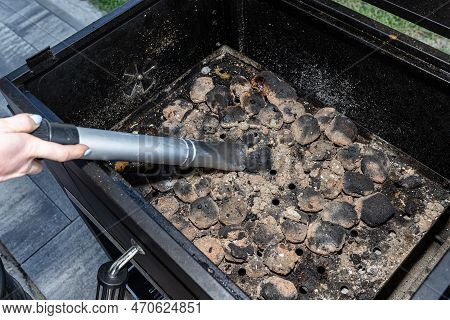 Cleaning A Dirty Grill While Standing On The Terrace And Emptying The Ashes.