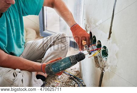 Close Up Of Male Hands In Work Gloves Installing Electrical Wire Cables In Wall With Electric Heat G