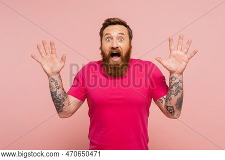 Thrilled Tattooed Man With Open Mouth Showing Wow Gesture And Looking At Camera Isolated On Pink.