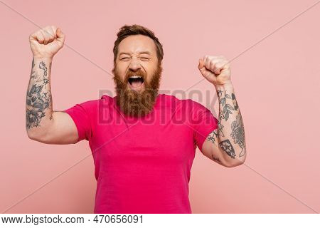 Joyful Bearded Man With Closed Eyes Showing Triumph Gesture And Screaming Isolated On Pink.