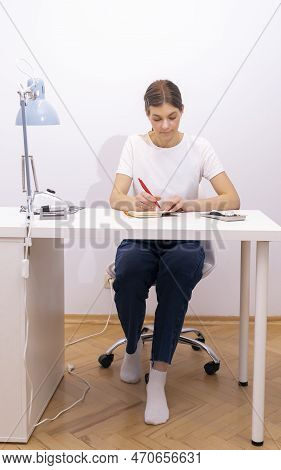 Nail Beautician Makes Notes In Notebook With Pen, Sitting At Workstation, Table In Nail Beauty Treat