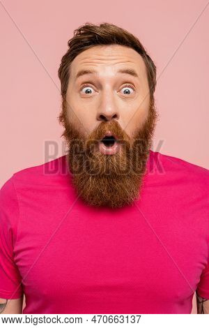 Amazed Bearded Man With Open Mouth Looking At Camera Isolated On Pink.