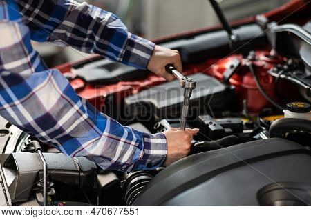 Female Auto Mechanic Unscrewing A Nut To Replace A Car Spark Plug.