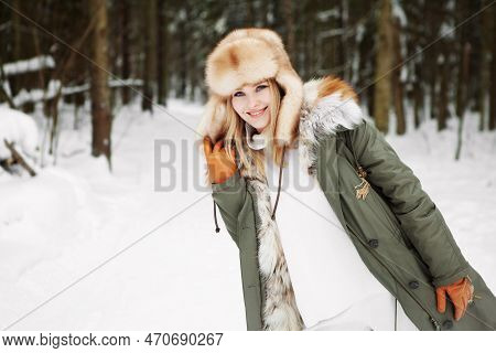 Young Woman Portrait At Winter Pine Snowy Forest Background, Wearing Fur Parka Coat, Ear Flaps Hat A