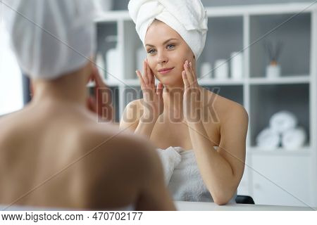 Young Woman Sits In The Bathroom In Front Of The Makeup Mirror And Does Cosmetic Procedures. Beautif