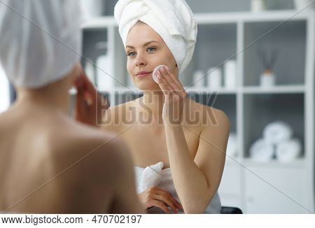 Young Woman Sits In The Bathroom In Front Of The Makeup Mirror And Does Cosmetic Procedures. Beautif