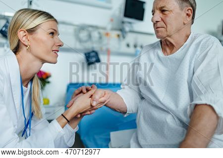Young Woman Doctor Holding Hand, And Talking With Her Patient.