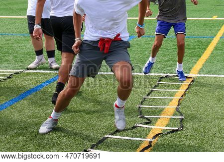 A Grou Of Boys Running The Ladder Drill At Preseason Summer Football Practice.