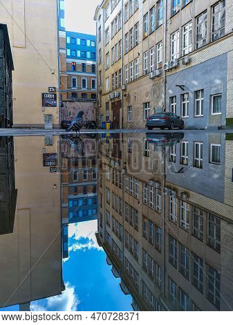Wroclaw, Poland - April 2022: Small Square Between High Old Tenement Buildings Reflected In Small Pu