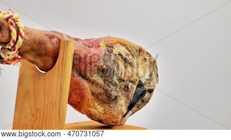 A Front Leg Of Serrano Ham Mapped On A Wooden Stand On A White Background.