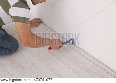 Professional Worker Using Nail Puller During Installation Of New Laminate Flooring Indoors, Closeup