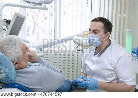 Elderly Man Sitting In Dentist Chair Talks About Dental Problems To Doctor. Male Dentist In Dental O