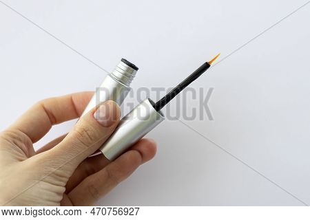 Eyebrow Serum For Women. Thin Brush Serum In A Girls Hand With Essential Oils And Peptides On Her Ey