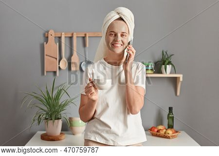 Indoor Shot Of Pretty Attractive Woman In A Cosmetic Mask And With A Towel On Her Head Posing In The