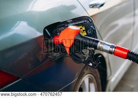 Fuel Nozzle Filling Petrol Into Car Tank At Gas Station. Image With Selective Focus