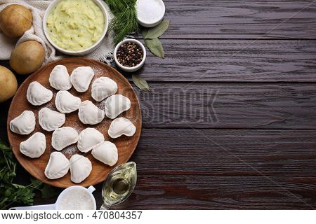 Raw Dumplings (varenyky) And Ingredients On Brown Wooden Table, Flat Lay. Space For Text