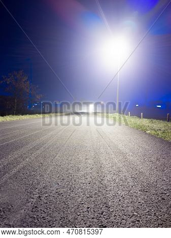 Low Angle View On A Empty Bicyclepath At Night With A Lighting Streetlight And Lensflare