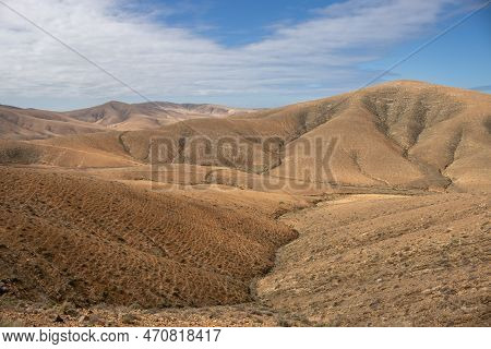 Shapes And Lines Of The Mountains Of The Volcanic Origin. Light Brown Color Of The Soil. Sky With Cl