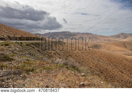 Shapes And Lines Of The Mountains Of The Volcanic Origin. Light Brown Color Of The Soil. Sky With Cl