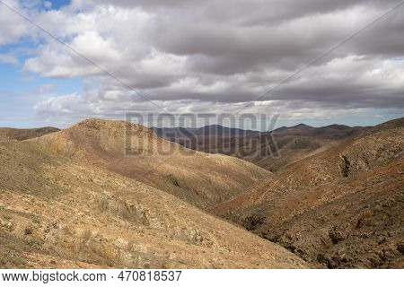 Shapes And Lines Of The Mountains Of The Volcanic Origin. Light Brown Color Of The Soil. Sky With Cl