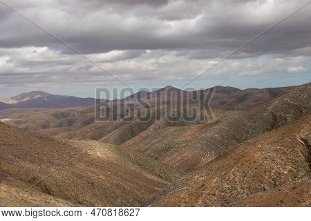 Shapes And Lines Of The Mountains Of The Volcanic Origin. Light Brown Color Of The Soil. Sky With Cl