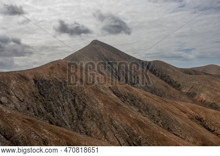Shapes And Lines Of The Mountains Of The Volcanic Origin. Light Brown Color Of The Soil. Sky With Cl
