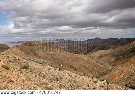 Shapes And Lines Of The Mountains Of The Volcanic Origin. Light Brown Color Of The Soil. Sky With Cl