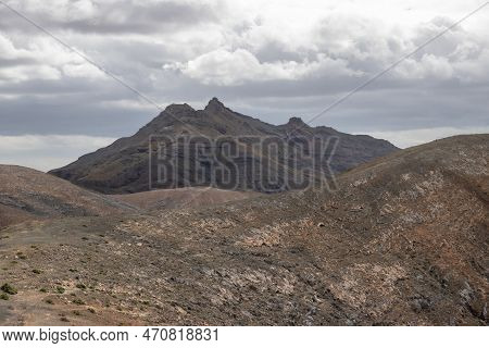 Shapes And Lines Of The Mountains Of The Volcanic Origin. Light Brown Color Of The Soil. Sky With Cl
