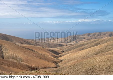 Shapes And Lines Of The Mountains Of The Volcanic Origin. Light Brown Color Of The Soil. Sky With Cl
