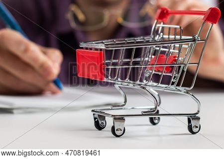 Man Calculates The Budget. Shopping Cart A On Table With Calculator And Paper. Budget Of Poor And Lo
