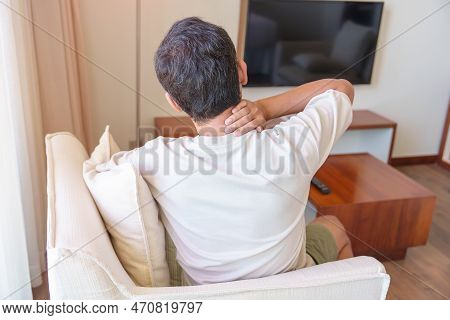 Man Having Neck And Shoulder Pain During Sitting On Sofa. Due To Fibromyalgia, Rheumatism, Scapular 