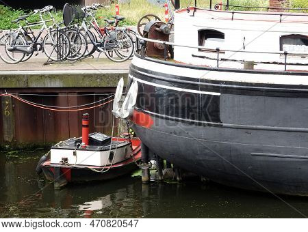 Amersfoort, Netherlands - July 23 2016 A Small Boat Docked At The Quay In Front Of A Large Ship. The