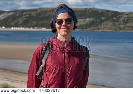 Smiling Woman In An Purpe Tourist Jacket On The Shore Of The Cold Northern Sea