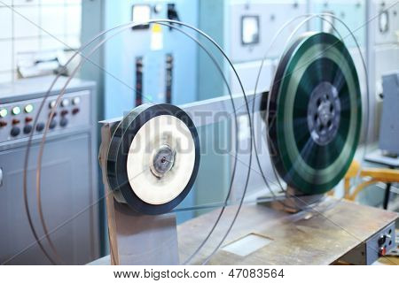 Reels with long videotape in small room of old movie theater.