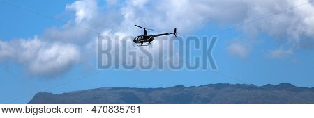 Panoramic View Of A Black Robinson R44 Raven Ii Flying Back To Its Heliport In Reunion Island.