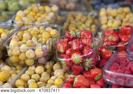 Close-up On Trays Of Raspberries, Strawberries And Mirabelle Plums On The Stall Of A Fruit Vendor.