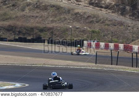 Two People Riding Go Karts On A Circuit.