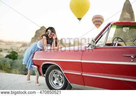 Beautiful Girl In Retro Style Posing Near A Vintage Red Cabriolet Car On Background Of Balloons In C
