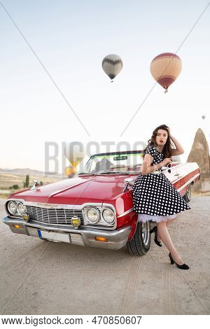 Beautiful Girl In Retro Style Posing Near A Vintage Red Cabriolet Car On Background Of Balloons In C