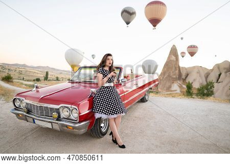 Beautiful Girl In Retro Style Posing Near A Vintage Red Cabriolet Car On Background Of Balloons In C