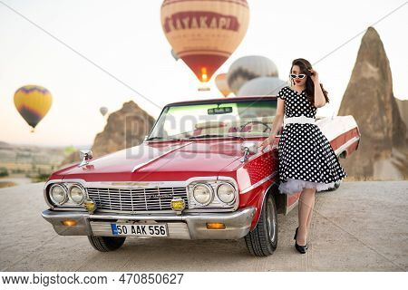 Goreme, Turkey, Cappadocia- June 30, 2021: Beautiful Girl In Retro Style Posing Near A Vintage Red C